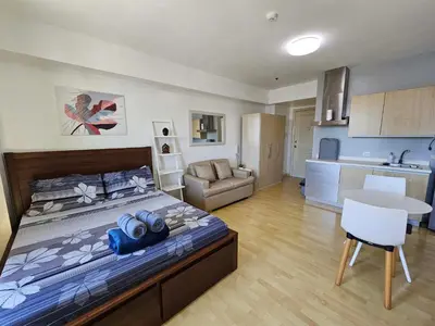 a bedroom with a large bed and a kitchen at N place at Soho Central in Manila