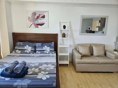a bedroom with a bed and a couch and a chair at N place at Soho Central in Manila