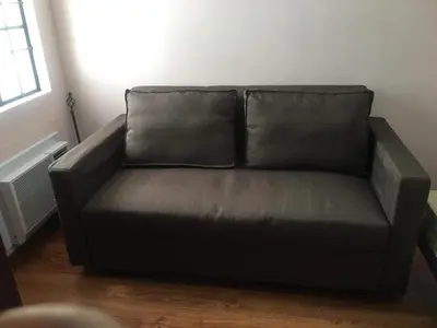 a black couch in a living room with a window at Affordable 2 BR 2 BA w/ Skycable, Netflix, & Amazon Prime in Manila