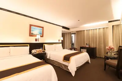 a hotel room with two beds and a chair at Bayview Park Hotel Manila in Manila