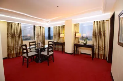 a hotel room with a table and chairs and windows at Bayview Park Hotel Manila in Manila