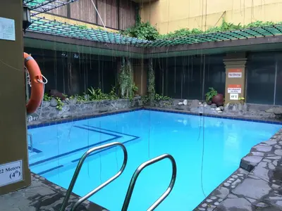 a large blue swimming pool in a building at Bayview Park Hotel Manila in Manila