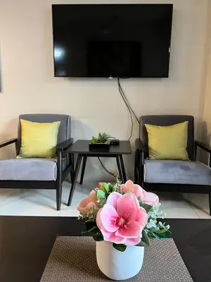 a living room with two chairs and a vase with flowers at Resorts World Condo in Manila