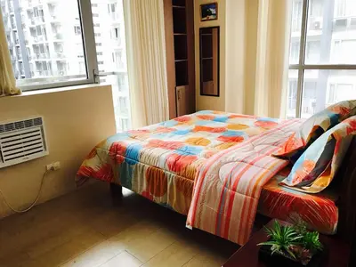 a bedroom with a bed with a colorful comforter and a window at Resorts World Condo in Manila