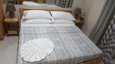 a bed with a gray and white comforter and pillows at 101 Newport Boulevard C1 in Manila