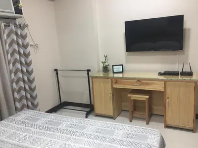 a bedroom with a desk with a television on the wall at 101 Newport Boulevard C1 in Manila