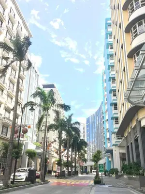 a city street with palm trees and tall buildings at 101 Newport Boulevard C1 in Manila