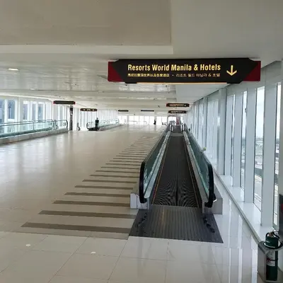 an empty walkway in a building with a escalator at 101 Newport Blvd Condotel in Manila