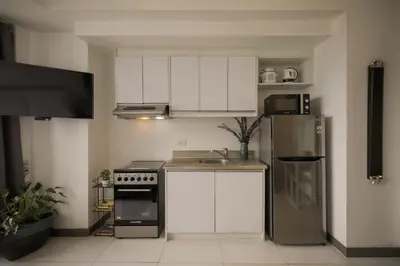 a kitchen with white cabinets and a stainless steel refrigerator at KL Tower Makati Apartments by PH Staycation in Manila