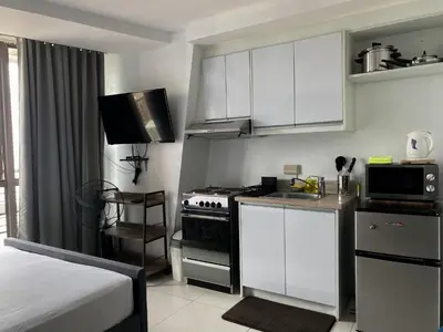 a small kitchen with white cabinets and a stove at KL Tower Makati Apartments by PH Staycation in Manila