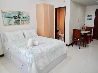 a bedroom with a large white bed and a table at Chillax Studio 101 Newport Boulevard in Manila