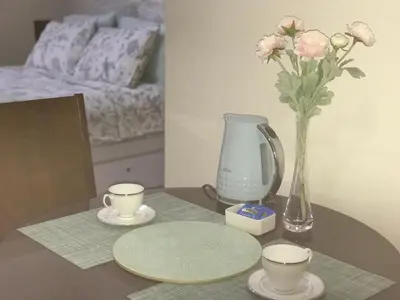a table with two cups and a vase with flowers at Chillax Studio 101 Newport Boulevard in Manila