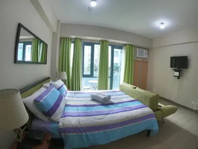 a bedroom with a bed and a chair and windows at Palm Tree 2 Villas-Cluster 2 Unit 3N in Manila