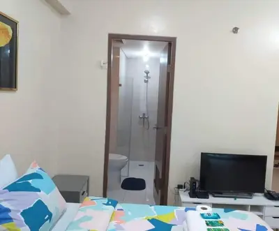 a bedroom with a bed and a television and a bathroom at Two Palm Tree Villas close to Manila Airport - Terminal 3 in Manila