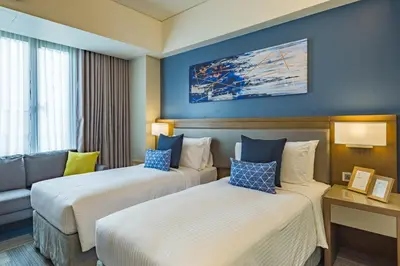 a hotel room with two beds and a couch at Citadines Bay City Manila in Manila