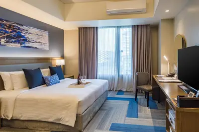 a hotel room with a bed and a desk and a television at Citadines Bay City Manila in Manila
