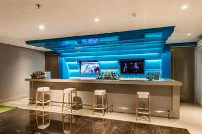 a bar in a room with blue walls and stools at Citadines Bay City Manila in Manila