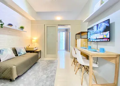 a living room with a bed and a desk and a television at Will’s Place at Jazz Makati in Manila
