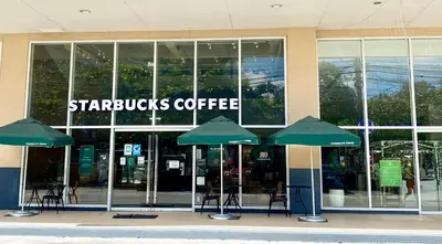a starbucks coffee building with chairs and umbrellas in front at Will’s Place at Jazz Makati in Manila