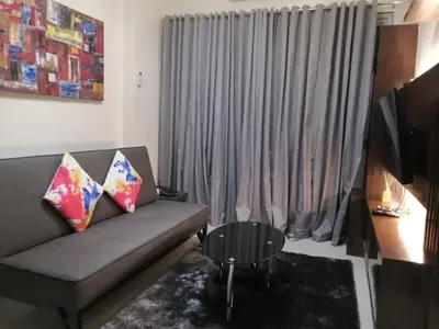 a living room with a couch and a large window at H&M One Palmtree Villas in Manila