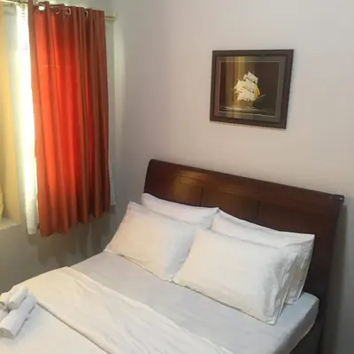 a bed with white sheets and pillows in a room at H&M One Palmtree Villas in Manila