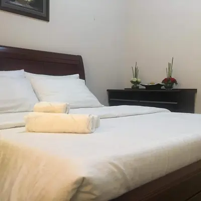 a bed with white sheets and two towels on it at H&M One Palmtree Villas in Manila