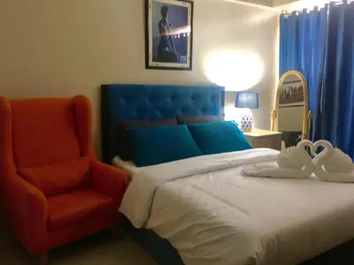 a bedroom with a bed with a blue headboard and a chair at H&M One Palmtree Villas in Manila