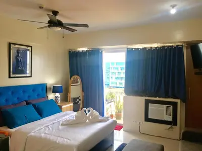 a bedroom with a blue bed and a window at H&M One Palmtree Villas in Manila