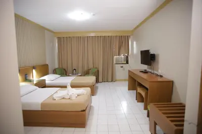 a hotel room with two beds and a desk at Hotel Soriente in Manila