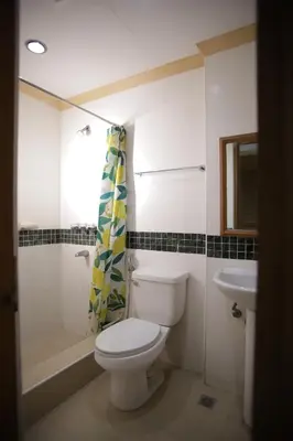 a white bathroom with a toilet and a sink at Hotel Soriente in Manila