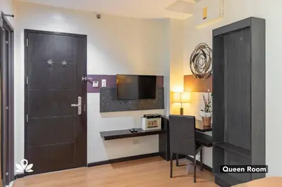 a room with a desk and a door and a television at Lorenzzo Suites Hotel Makati in Manila