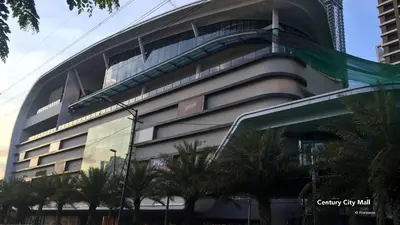 a building with palm trees in front of it at Lorenzzo Suites Hotel Makati in Manila