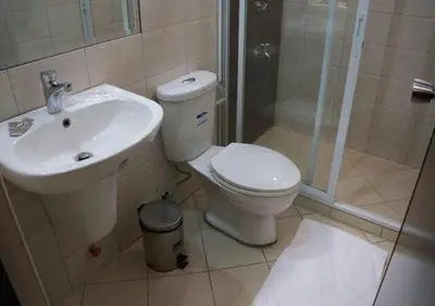 a bathroom with a toilet and a sink and a shower at Lorenzzo Suites Hotel Makati in Manila