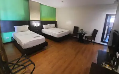 two beds in a room with green and white walls at Lorenzzo Suites Hotel Makati in Manila