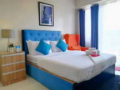 a bedroom with a large bed and an orange chair at The Palm Tree Condotel Manila Airport in Manila
