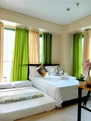 two beds in a room with green curtains at The Palm Tree Condotel Manila Airport in Manila