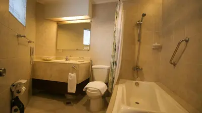 a bathroom with a sink and a toilet and a tub at Royal Bellagio Hotel in Manila