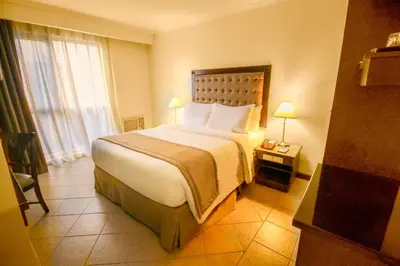 a hotel room with a large bed and a window at Royal Bellagio Hotel in Manila