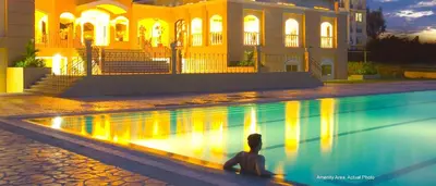 a man sitting next to a swimming pool in front of a building at CHATEAU ELYSEE a6 near AIRPORT Wifi Kitchen in Manila