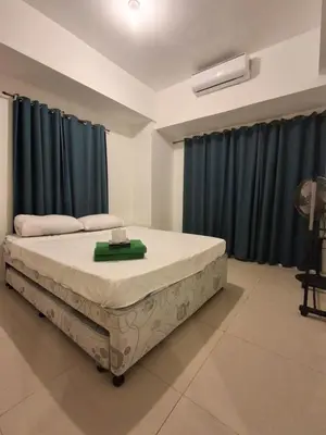 a bedroom with a large bed with blue curtains at Spacious 2BR in Jazz Residences Makati in Manila
