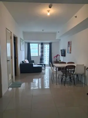 a living room with a couch and a table and chairs at Spacious 2BR in Jazz Residences Makati in Manila
