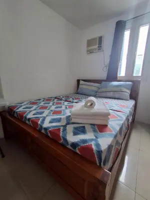 a bed with a wooden frame and a white object on it at Spacious 2BR in Jazz Residences Makati in Manila