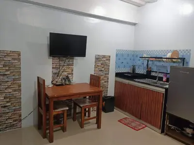 a kitchen with a table and a television on a wall at Mavs transient inn kassel residences in Manila