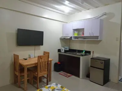 a small kitchen with a table and a television on the wall at Mavs transient inn kassel residences in Manila