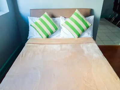 a bed with two green and white pillows on it at Forbes Area BGC Taguig Manila in Manila