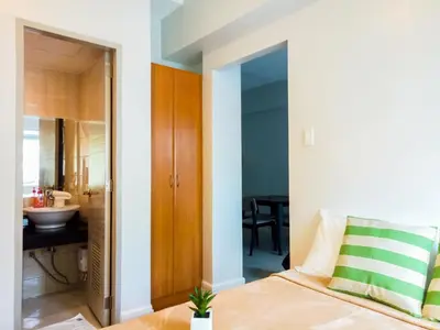 a bedroom with a bed and a bathroom with a sink at Forbes Area BGC Taguig Manila in Manila