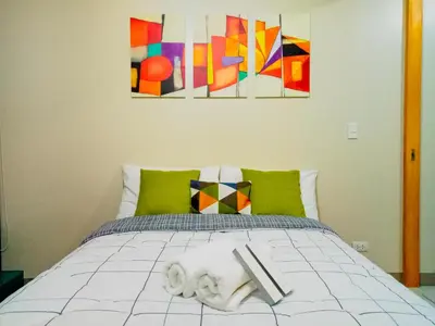 a bedroom with a bed with paintings on the wall at Uptown Mall Area Fort Bonifacio Manila in Manila
