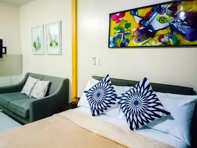 a bedroom with a bed with blue and white pillows at Uptown Mall Area Fort Bonifacio Manila in Manila
