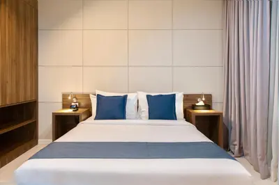 a bedroom with a large bed with blue pillows at The Sphere Serviced Residences Managed by HII in Manila