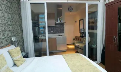 a bedroom with a white bed and a kitchen at AZURE C5 MAN-MADE BEACH BALCONY Multiple Units in Manila